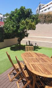 a wooden table and chairs on a deck with a tree at Vila Azul in Sesimbra