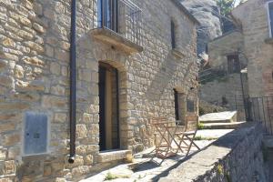 un edificio de piedra con 2 sillas sentadas fuera de una ventana en Casa nella Roccia, en Castelmezzano