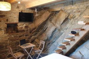 Habitación con pared de piedra, escaleras y TV. en Casa nella Roccia, en Castelmezzano