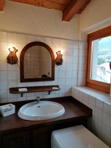 een badkamer met een wastafel, een spiegel en een raam bij Theatrum in Aosta