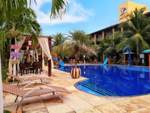 una piscina en un complejo con sillas y un hotel en Hotel Jangadas, en Águas Belas
