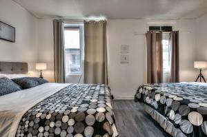 a bedroom with two beds and two windows at 100 METERS to SUBWAY - Montcalm condos in Montréal