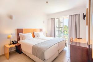a bedroom with a large bed and a balcony at Aquamar Albufeira Aparthotel in Albufeira +35 photos