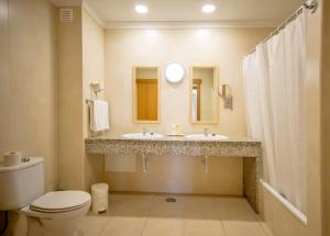a bathroom with two sinks and a toilet and a mirror at Aquamar Albufeira Aparthotel in Albufeira