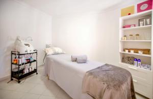 a white bedroom with a bed and shelves with products at Aquamar Albufeira Aparthotel in Albufeira