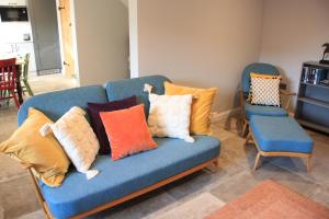 a blue couch with pillows on it with two chairs at Charming and luxury retreats on our farm in Billingshurst