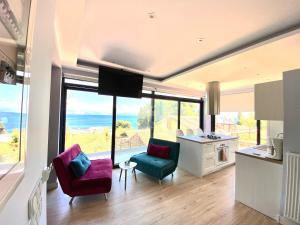a living room with two chairs and a kitchen with large windows at Private Sea view house Belonika in Benitses +27 photos