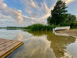 a boat parked next to a dock on a lake at Domek z basenem na Mazurach in Giże