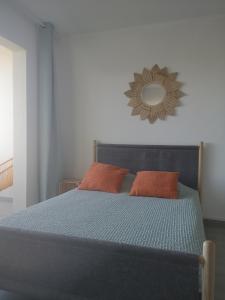 niebieskie łóżko z 2 pomarańczowymi poduszkami i lustrem w obiekcie ESCALE AU GRAU DU ROI w mieście Le Grau-du-Roi