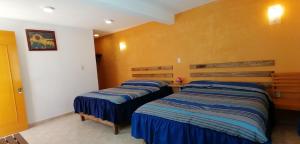 - 2 lits dans une chambre aux murs jaunes dans l'établissement CASA LUPITA, à Mineral del Monte