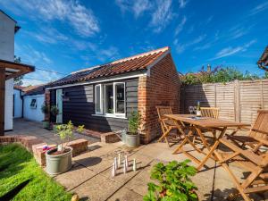 a small patio with a wooden table and chairs at Horatio’s in Worstead