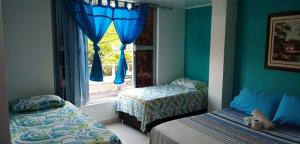 a bedroom with two beds and a window with blue walls at Hotel Español Neiva in Neiva +137 photos