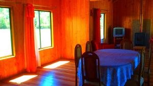 a dining room with a table and two windows at Cabañas Los Canelos Pucon, Hermosa Granja de 20 hectaréas a orillas del Río Liucura in Pucón