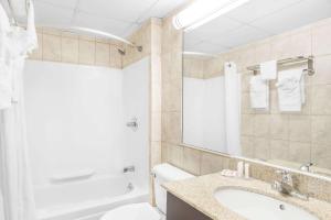 a bathroom with a sink and a tub and a mirror at Howard Johnson by Wyndham North Bergen in North Bergen