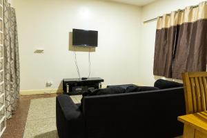 Una sala de estar con un sofá y un televisor de pantalla plana. en Brannic Lodge, en Accra