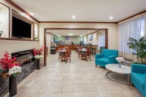 a living room with tables and chairs and a fireplace at Baymont by Wyndham Grand Rapids Airport in Grand Rapids