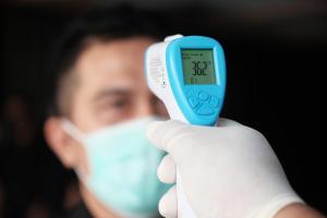 a man in a white glove holding a blue thermometer at Lovina Inn Batam Centre in Batam Center