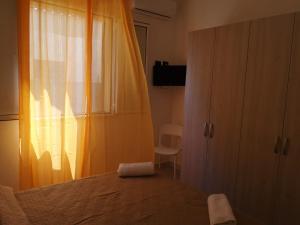 a bedroom with a bed and a window and a chair at Appartamento a San Vito lo capo in San Vito lo Capo
