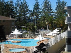 a swimming pool with white umbrellas and chairs at 2nd Avenue Beachside Apartments in Gold Coast
