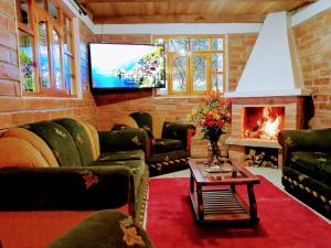 sala de estar con chimenea y TV en El Encanto del Taita Imbabura, en Otavalo