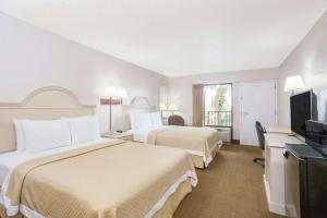 a hotel room with two beds and a flat screen tv at Days Inn & Suites by Wyndham Navarre - near Beaches Hurlburt in Navarre