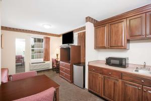 a kitchen with wooden cabinets and a kitchenette with a microwave at Days Inn by Wyndham Trumann AR in Trumann