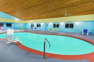 a large swimming pool with blue chairs and tables at Days Inn by Wyndham West Des Moines in West Des Moines