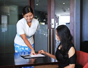 two women standing around a table with a laptop at Suites by Watermark Hotel and Spa in Jimbaran