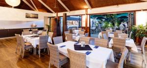 una sala da pranzo con tavoli e sedie bianchi di Luxury Executive Apartment at Broome Cable Beach a Broome