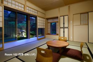 Zimmer mit einem Tisch, Stühlen und Fenstern in der Unterkunft Luck You Kyoto in Kyoto