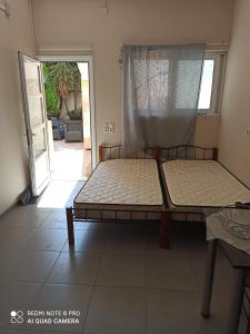 two beds in a room with a door to a patio at studio room in Koropi