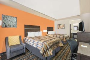 una habitación de hotel con 2 camas y una silla en Days Inn by Wyndham Dilley, en Dilley