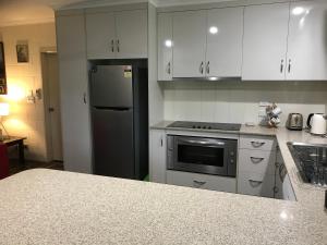 a kitchen with white cabinets and a black refrigerator at Royal Palm Cottage, Entire two bedroom 2 bathroom house with Pool in Mission Beach