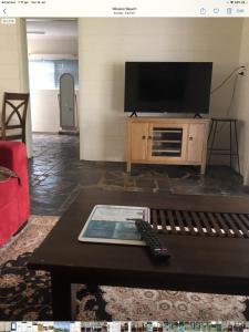 a living room with a flat screen tv and a coffee table at Royal Palm Cottage, Entire two bedroom 2 bathroom house with Pool in Mission Beach