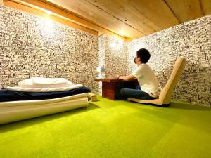 a man sitting at a desk in a room at Guest House MARUYA in Atami
