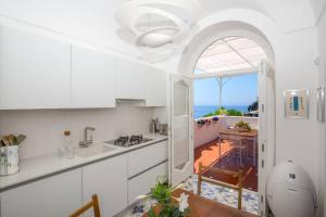 a kitchen with white cabinets and a view of the ocean at CASA BAKER luxury apartment in Positano
