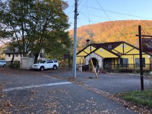a yellow house with a car parked in front of it at SkiHolic by TSH in Shinano