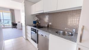 
a kitchen with a white counter top and white cabinets at Oaks Glenelg Plaza Pier Suites in Adelaide
