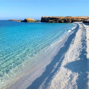 a sandy beach with blue water and rocks at Il Vecchio Ginepro in Capoterra