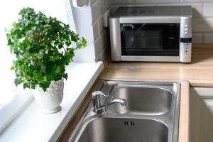 a kitchen sink with a microwave and a potted plant at Nautical Sea Apartment in Gdynia +26 photos
