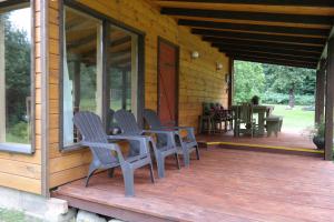 vier Stühle auf der Veranda einer Blockhütte in der Unterkunft Latava in Anykščiai