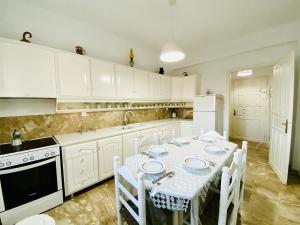 a kitchen with white cabinets and a table with chairs at Deluxe Studios & Suites Ageri-Milos in Adamantas