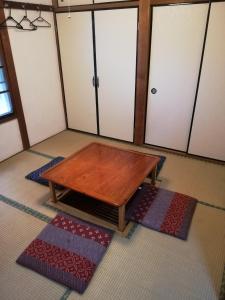 a coffee table in a room with some rugs at 昭和レトロタイムスリップ古民家ゲストハウス舞妓まいこ in Kyoto
