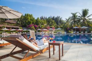 una pareja acostada en tumbonas junto a una piscina en Victoria Phan Thiet Beach Resort & Spa, en Mui Ne