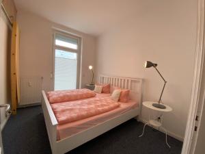 Schlafzimmer mit einem Bett mit rosa Bettwäsche und einem Fenster in der Unterkunft Appartementhaus Ennen in Norderney