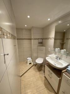 ein Badezimmer mit Waschbecken, Toilette und Spiegel in der Unterkunft Appartementhaus Ennen in Norderney