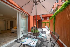 een patio met een tafel en stoelen en een parasol bij Smart House S.Orsola - Garage & Garden in Bologna
