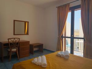 a bedroom with a bed and a desk and a window at Vivaldi Appartamenti in Marinella di Selinunte