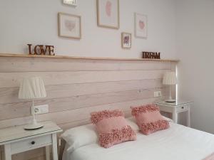 a bedroom with a white bed with two pink pillows at El Nogal Home in Málaga