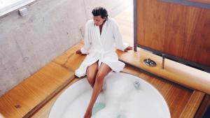 a woman in a bathrobe sitting on a bath tub at Vilavella Hotel & Spa in Vilavella